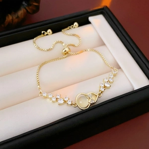 Detail eines verstellbaren Gold-Armbands mit Zirkonia-Schleife und Katzenaugenstein
