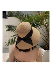 Detail of wide black satin bow on light khaki straw sun hat with large brim