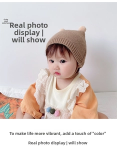 Close-up of baby knitted warm hat featuring cute double plush pom-poms on the top