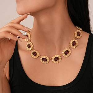 Detail of vintage gold necklace with oval red gemstone pendants and floral accents