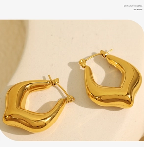 Close-up of gold titanium steel C-shaped geometric earrings with polished finish