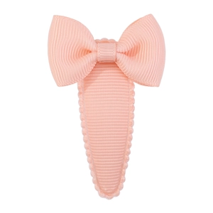 Close-up of peach pink grosgrain ribbon bow hair clip with scalloped fabric-wrapped edge
