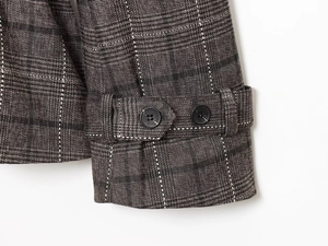 Détail du poignet d'un manteau en laine mélangée à carreaux avec bride décorative boutonnée