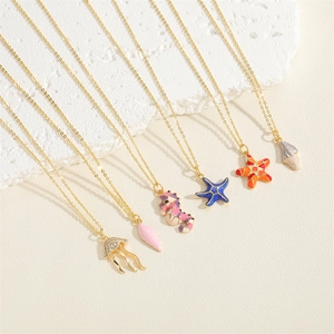 Gold ocean necklaces with starfish, seahorse and jellyfish pendants on beach sand