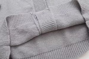 Detail eines grauen Strickpullovers mit feiner Rippung und hochwertiger Stofftextur