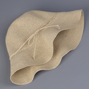 Detail of hand-woven straw sun hat showing intricate mesh texture and wavy brim design
