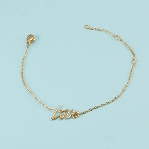 Détail d'un bracelet doré en acier inoxydable avec pendentif Love sur fond bleu clair