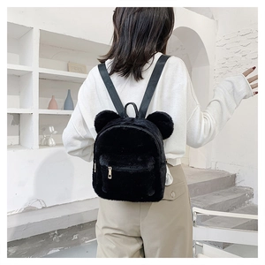 Detail of a mini black plush backpack with bear ears shown on a female model