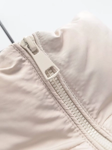 Macro view of a smooth beige zipper detail and fine fabric texture on a casual vest