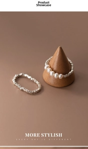 Macro detail of silver ring set with textured finish and white pearls on wooden stand