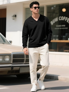 Detail of black V-neck cable knit sweater featuring textured vertical knit pattern on sleeve