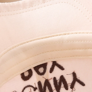 Detailed macro view of beige cotton twill fabric with brown embroidered lettering for caps