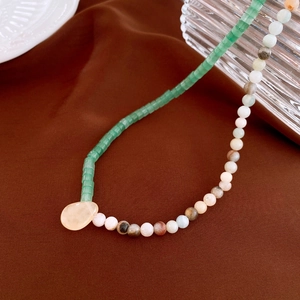 Detail of beaded necklace with green cylinders, colorful round beads and yellow pendant