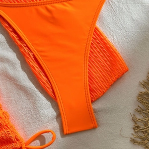 Detailed close-up of vibrant orange bikini bottom fabric with premium stitching