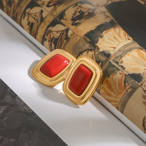 Macro view of vintage gold earrings with rectangular red gems on a retro magazine