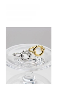 Detail of stacked gold and silver geometric beaded rings on a clear glass display stand