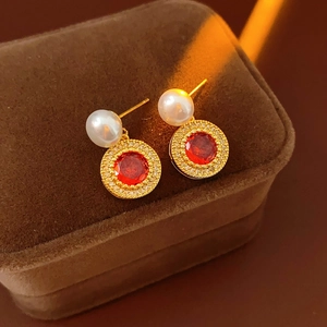 Détail de boucles d'oreilles vintage en or et perle avec zircon rouge en boîte luxe