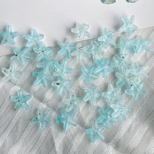 Macro view of translucent light blue starfish beads with gold glitter for DIY crafts