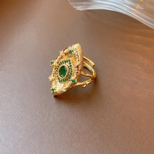 Vintage gold ring with emerald eye design and intricate textured sunburst detailing
