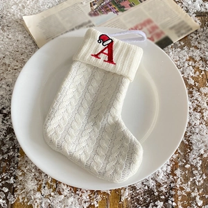 White knitted Christmas stocking with red embroidered letter A and festive hat decoration