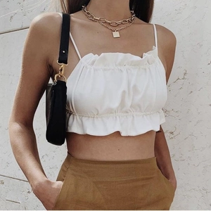 Close-up of white cropped tank top featuring ruffled chest detail and thin straps