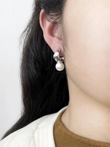 Gros plan de boucles d'oreilles crochet argentées avec perle pendante sur un modèle