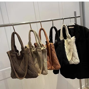 Detail view of woven knit tote bags in five colors hanging on metal hangers