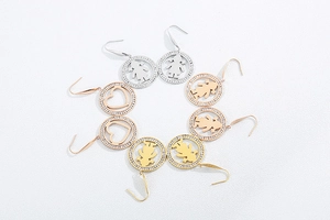 Detail of round stainless steel drop earrings with zircon inlay and heart patterns