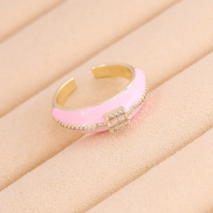 Dettaglio dell'anello dorato con smalto rosa e zircone su scatola di velluto