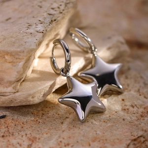 Gros plan de boucles d'oreilles étoile en argent poli sur une pierre jaune naturelle
