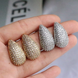 Close-up of gold and silver teardrop stud earrings with full pavé cubic zirconia
