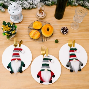 Christmas gnome cutlery holders with striped hats on wooden table for festive decoration
