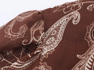Dettaglio macro del tessuto in chiffon marrone con motivo paisley bianco e trama fine