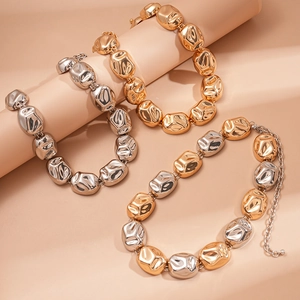 Exaggerated metal chain necklaces in gold and silver with irregular lava texture