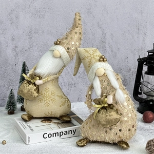 Pair of festive Christmas gnomes in gold sequins with white beards on a decor book
