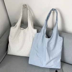 Close-up of floral tote bags with black and blue polka dot patterns on a sofa