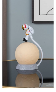 Detailed view of creative astronaut floating on a desk lamp with glowing moon light