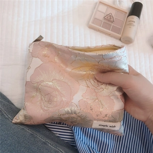 Macro detail of elegant pink jacquard floral makeup bag with simple wish fabric label