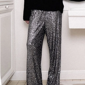 Close-up of sparkling silver sequin fabric on these high-waisted wide leg trousers