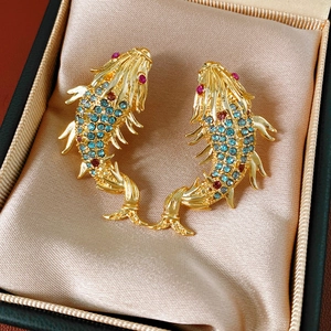 Macro detail of vintage gold koi fish earrings with blue and red crystal scales