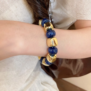 Close-up of geometric acrylic beaded bracelet with gold blocks and blue celestial beads