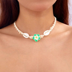 Detail of bohemian choker featuring green clay flower and white shells on white woven cord