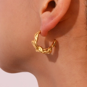 Golden irregular crescent metal earrings with fluid crinkle texture worn by a model