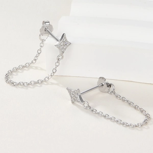 Elegant silver star stud earrings with diamond inlay and chain detail on white stone
