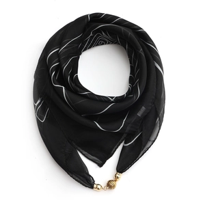 Detail of black silk scarf with white patterns and a functional golden magnetic buckle
