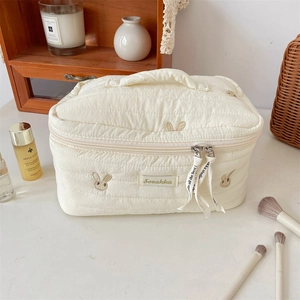 Close-up of cute rabbit embroidery on cream quilted fabric with detailed metal zipper