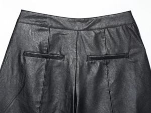 Detail view of black faux leather shorts showing rear pocket stitching and pebbled texture