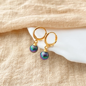 Detail of 18K gold plated hoop earrings with iridescent peacock green pearls on ceramic