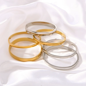 Minimalistische offene Armreifen aus Titanstahl in Gold und Silber auf weißer Seide