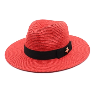 Detail of red straw jazz hat featuring black ribbon and golden bee metal buckle